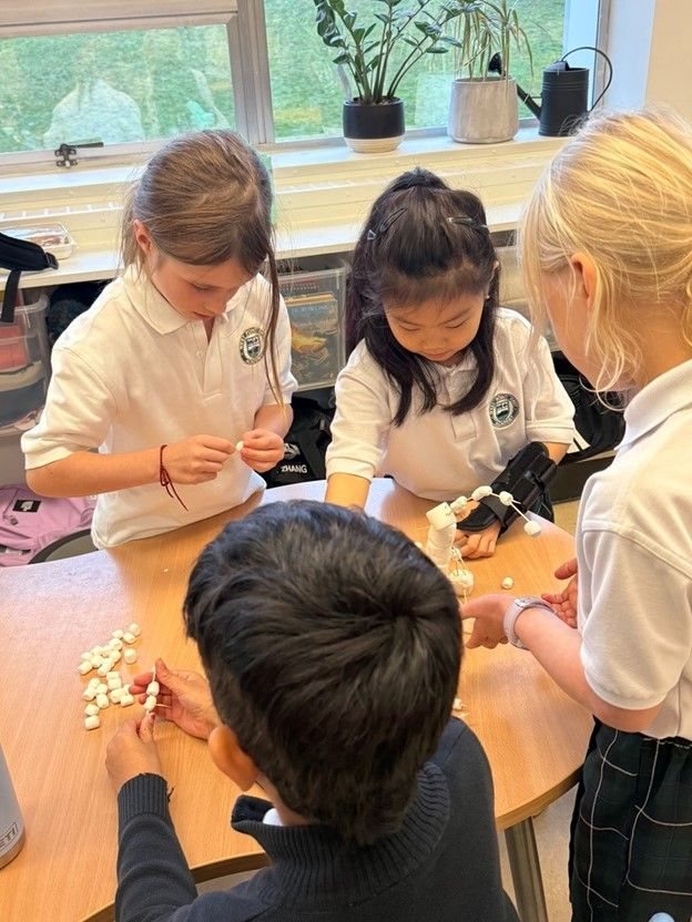 Students around a table working together on marshmallow-and-toothpick structures.